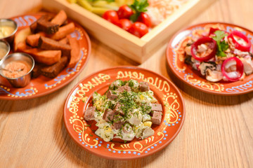 Covered table with traditional Ukrainian food, side view, horizontal. Healthy vegetable salad with croutons.