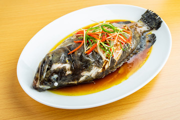 A dish of Cantonese steamed grouper on wooden table