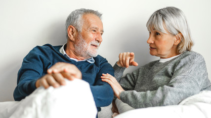 Senior happy couple relaxing and talking together lying on bed in bedroom at home.Retirement couple concept