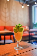 Refreshing cold citrus drink with mint. Cold summer beverage served in a glass. ALcohol cocktail on a wooden table