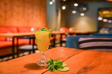 Refreshing cold citrus drink with mint. Cold summer beverage served in a glass. ALcohol cocktail on a wooden table