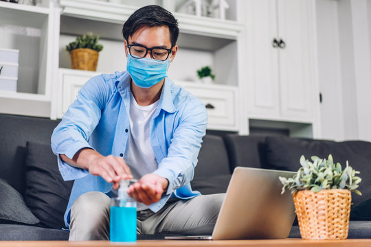 Young Man Washing Hands With Alcohol Gel In Quarantine For Coronavirus Wearing Protective Mask With Social Distancing And Using Laptop Computer Working At Home.work From Home And Covid19 Concept