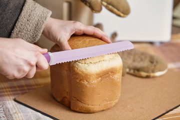 Hostess  holds  big knife in front of  loaf of bread