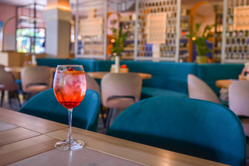 A glass with the red citrus cocktail. Alcohol summer beverage in a wine glass. Refreshing drink with ice.