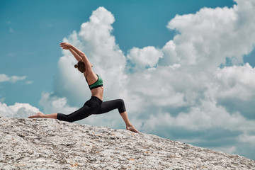 Yoga time. Sport. Healthy lifestyle. Woman trains in sportswear. Flexible body. Beautiful cloudy sky. Workout on nature