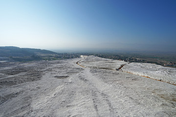 Natural landscape and Thermal pools of Pamukkale (Cotton castle) mineral-rich thermal waters flowing down white travertine terraces on a nearby hillside formed by ancient hot springs- Denizli, Turkey
