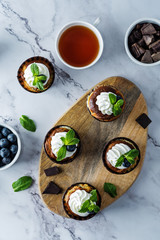 Chocolate cream cheese cupcakes with whipped cream, mint leaves and blueberry