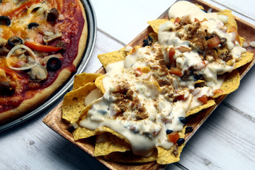 Freshly made nachos and pizza with cheese, tomato sauce, vegetable and meat toppings