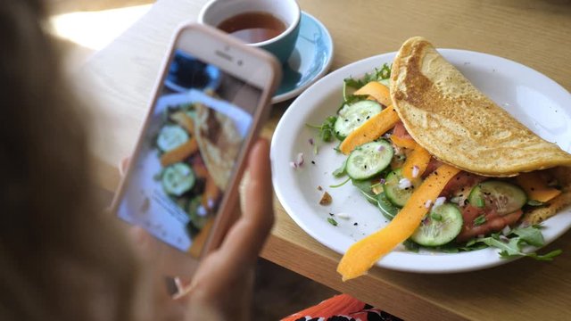 Hands taking picture of healthy organic vegan breakfast with smartphone. Vegan omelette with vegetables. Vegan food porn concept.