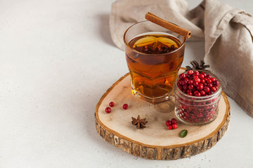 Hot tea with spices, Apple and berries in a transparent glass mug on a wooden stand. concept home comfort. Copy space