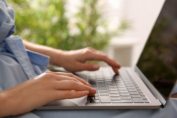 Woman working with modern laptop indoors, closeup