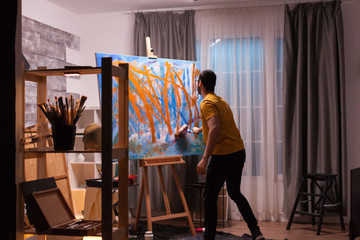 Successful painter in art workshop creating a masterpiece. Modern artwork paint on canvas,...