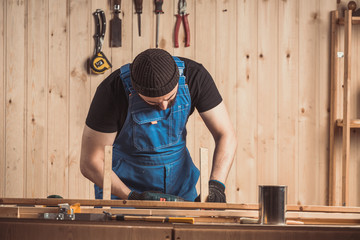 Home repair concepts, close up. Handicraft Carpentry. Cabinet-maker hands drilling a wooden plank using screwdriver on the working table in the workshop