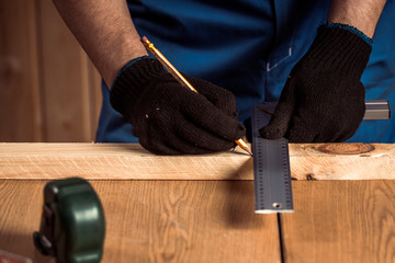 close-up of a male joiner measures with a ruler and a pencil dimensions are required for the...