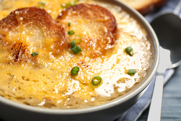 Tasty homemade french onion soup served in ceramic bowl, closeup