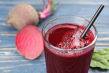 Freshly made beet juice in glass on blue table, closeup