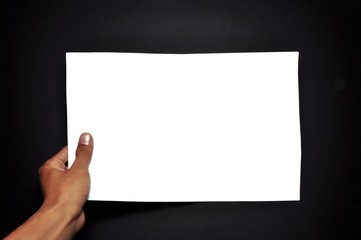 Hand holding white paper isolated on black background. Close-up hand holding blank sheet