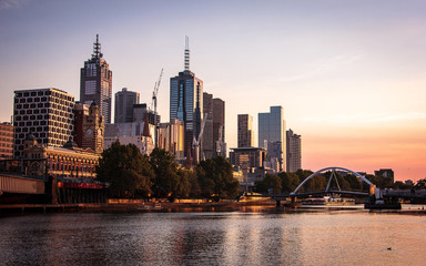 Melbourne in the golden hour, colorful sky, river, bridge and buildings.