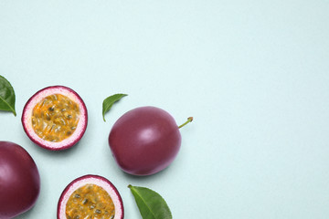 Fresh ripe passion fruits (maracuyas) with leaves on light background, flat lay. Space for text