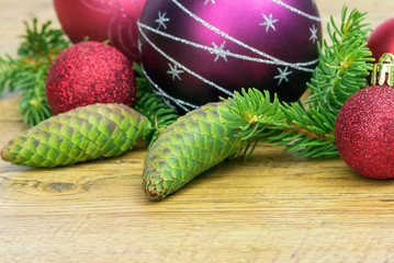 Composition with fresh spruce cones and New Year's multi-colored toys on a wooden background.