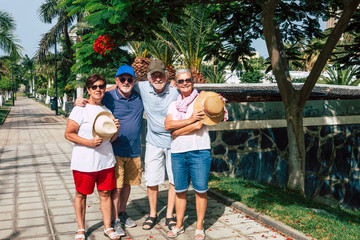 Fototapeta premium Family group of four senior people smiling enjoying sunny day in outdoor vacation hugging in the public park