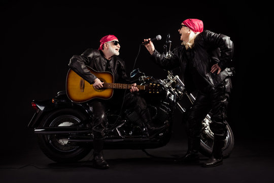 Full body photo of aged bikers man lady duet couple chopper moto rock festival meeting play guitar sing songs youth years group wear rocker leather jacket isolated black color background
