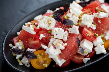 Salad with grapefruit, feta cheese, cherry tomatoes, nuts and red basil, close-up, selective focus
