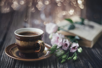 Cup of coffee, book and flowers on a wooden table. Background. Vintage. Postcard.