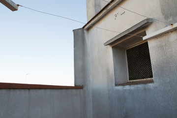 Detalle del terrado de un bloque de pisos viejo. Detalle de la ventana del ascensor y de los cables para tender