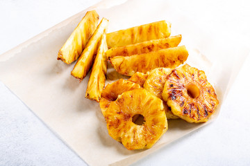 Heap of grilled pineapple slices on white background.