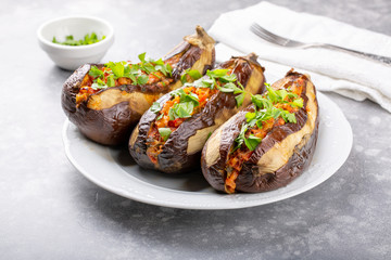 Whole eggplant stuffed with vegetables on white plate on grey background . Imam bayildi, Turkish cuisine.