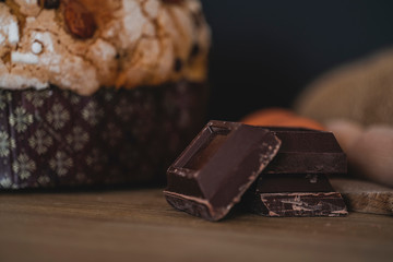 Panettone, typical Italian Christmas cake with chocolate and almonds. In the background the ingredients used to make panettone, eggs, flour, chocolate.

