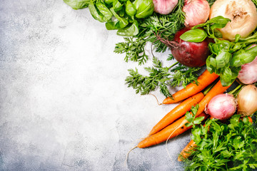 Assortment of fresh root vegetables and spicy herbs. Healthy food, summer cooking concept. Gray background with copy space. Top view