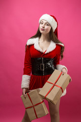 Beautiful young woman in Santa Claus costume against the red background.