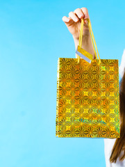 woman holds golden gift bag in hand