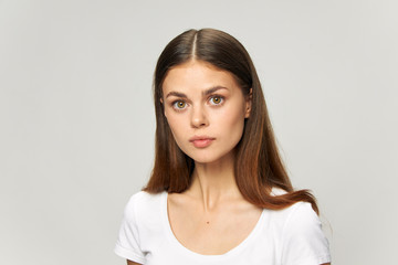 Brunette girl in a light T-shirt looks forward model close-up 