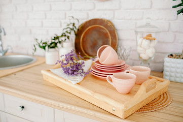 Light wooden kitchen interior. Beautiful kitchen interior design. pale pink tableware plates cups
