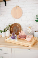 Light wooden kitchen interior. Beautiful kitchen interior design. pale pink tableware plates cups