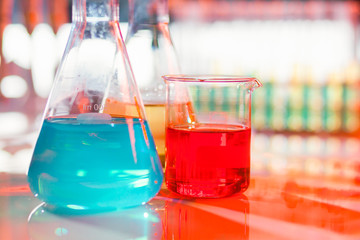 Backlit laboratory test flask containing colorful liquids.