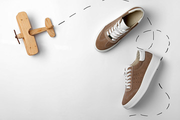 Stylish shoes and wooden toy plane on white background, top view - Powered by Adobe