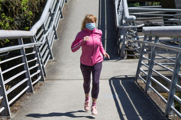 woman with medical mask running through the city, sport concept in the new normal