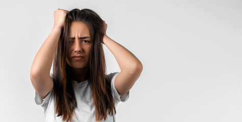 Photo of girl with long chestnut hairs with closes eyes, holding hands on head. Problems, fear, fobia concept.Copy space