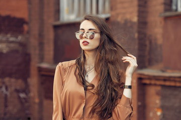 Portrait of young woman with curly hair in sunglasses and earphones on the street