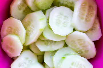 Sliced, green cucmbers in purple bowl