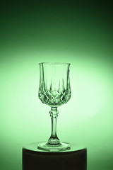 Wineglass on the light background. Fine cristal glassware concept. Vertical, toned in green