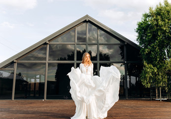 An incredible bride lifting her lush dress up creates the image of an angel. Summer terrace for...