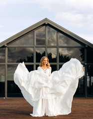 An incredible bride lifting her lush dress up creates the image of an angel. Summer terrace for...