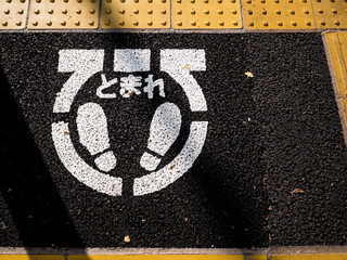 歩道にプリントされた「とまれ」の標識