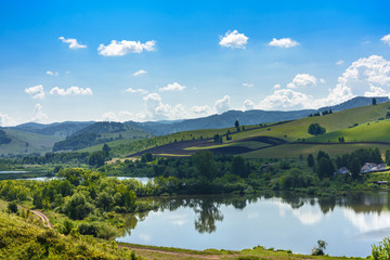 Landscape with hills and lake on a Sunny day, blue sky with clouds. Russia, Altai territory