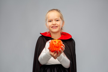 halloween, holiday and childhood concept - happy smiling girl in black dracula cape or costume with...